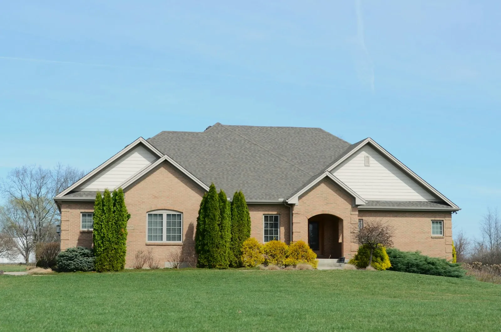 A brick house with a freshly mown, striped front lawn