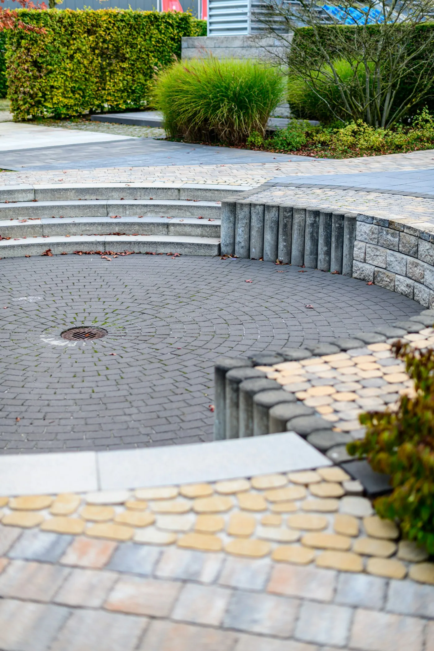 A curved paver seating area with stone steps and greenery